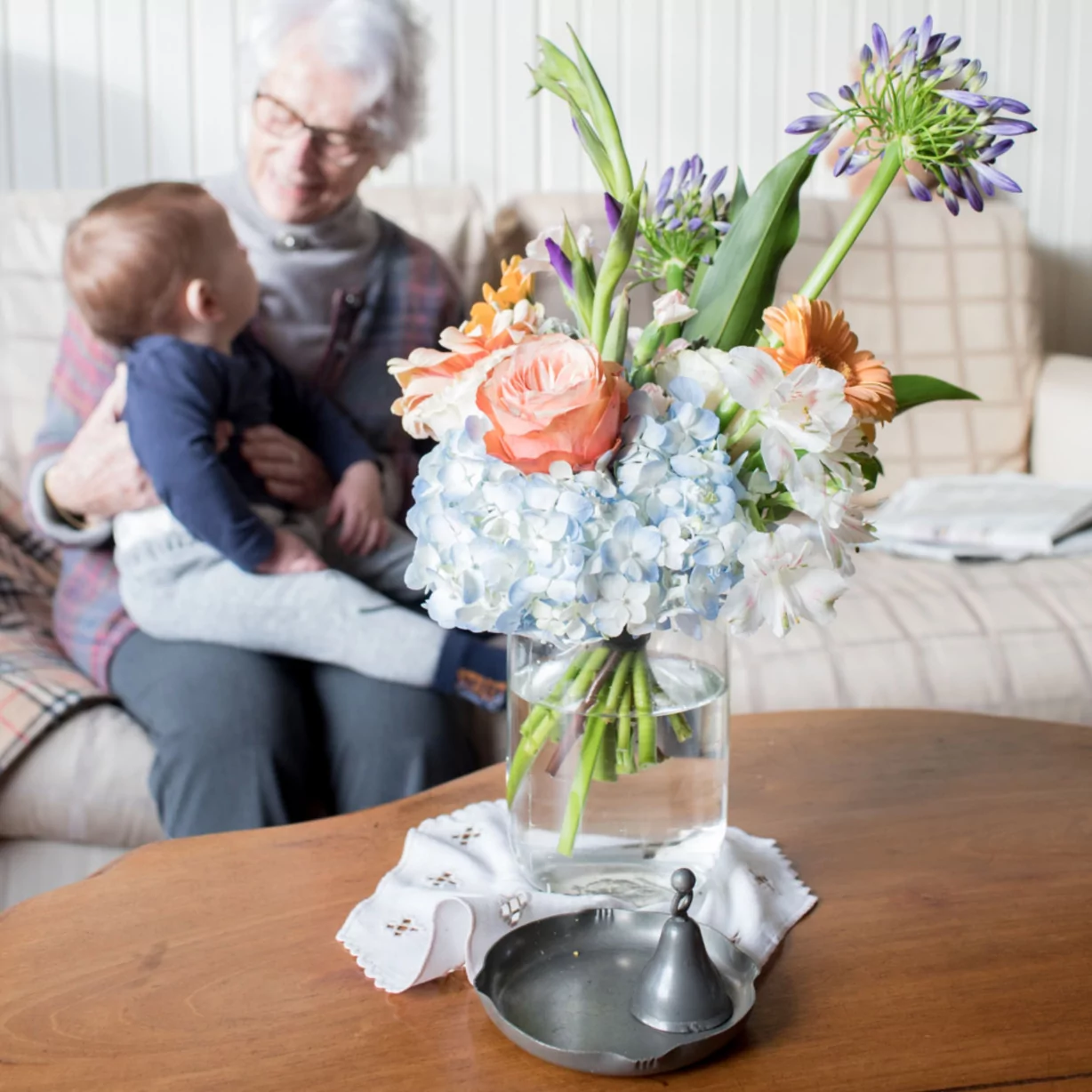 Une grande -mère avec son petit enfant derrière un vase avec un bouquet de fleurs fait par un fleuriste (1)-1228 Grand mère avec son petit enfant