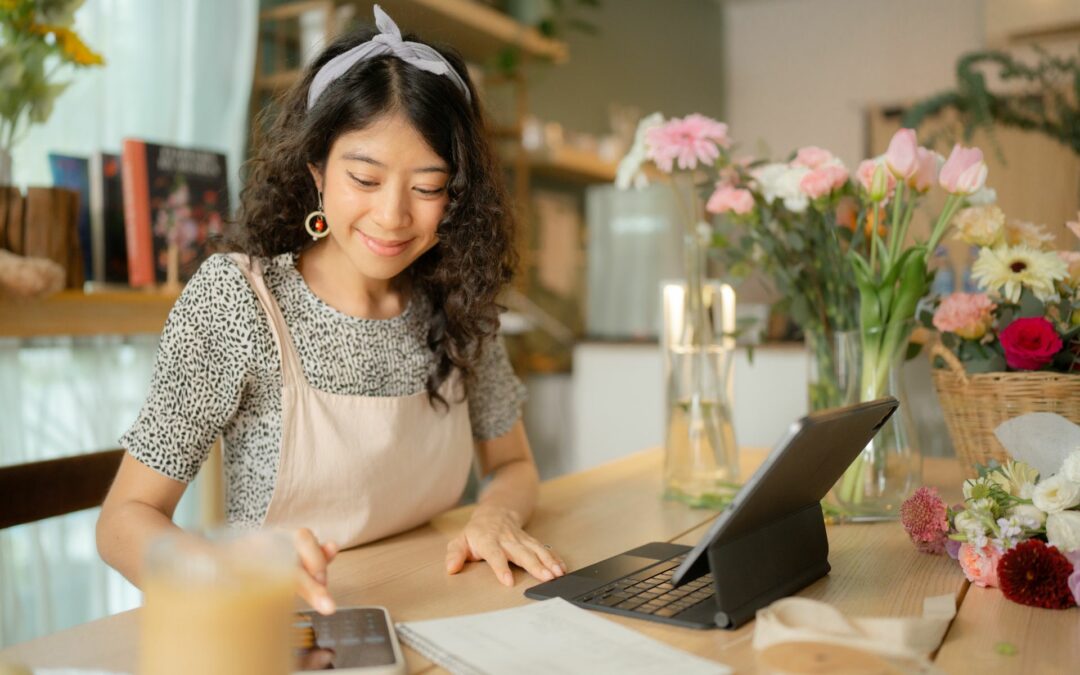 5 conseils pour attirer des nouveaux clients : Fleuriste avec une tablette dans sa boutique qui est heureuse